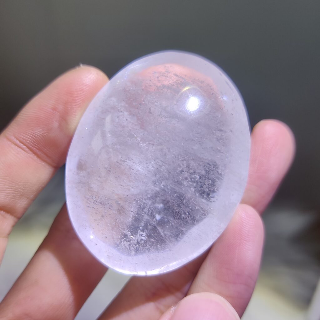 Clear quartz palm stone held to show translucency
